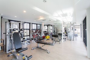 Une salle de sport moderne dotée de divers appareils d’entraînement, de grandes fenêtres et d’un aménagement propre et spacieux.