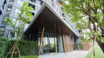 Un edificio moderno con una estructura de techo triangular distintiva, grandes ventanales y un jardín bien cuidado.