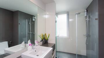Un baño moderno con ducha de vidrio, un espejo grande y encimera de granito.