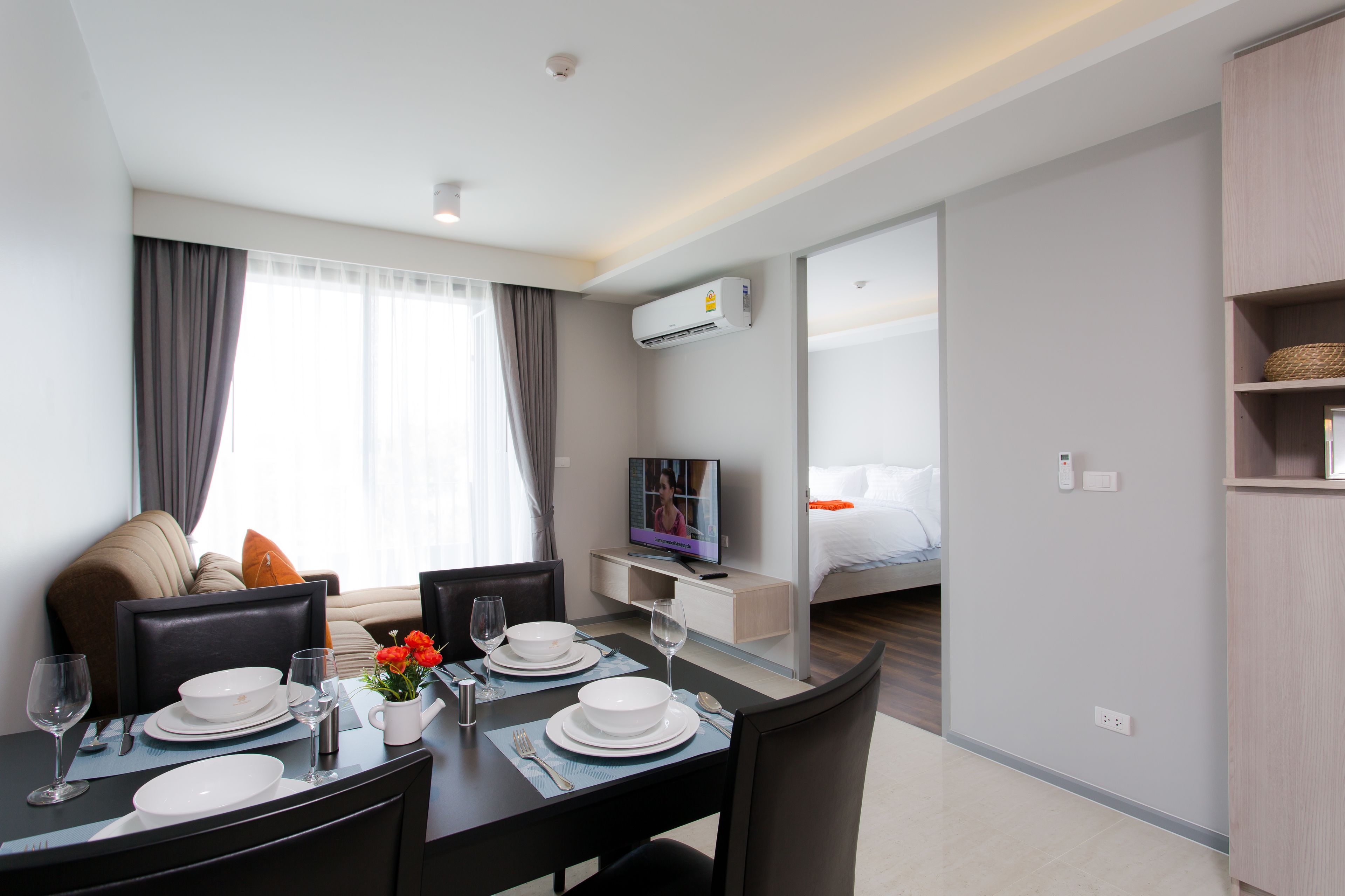 Una habitación de hotel moderna con comedor, televisor y cama.