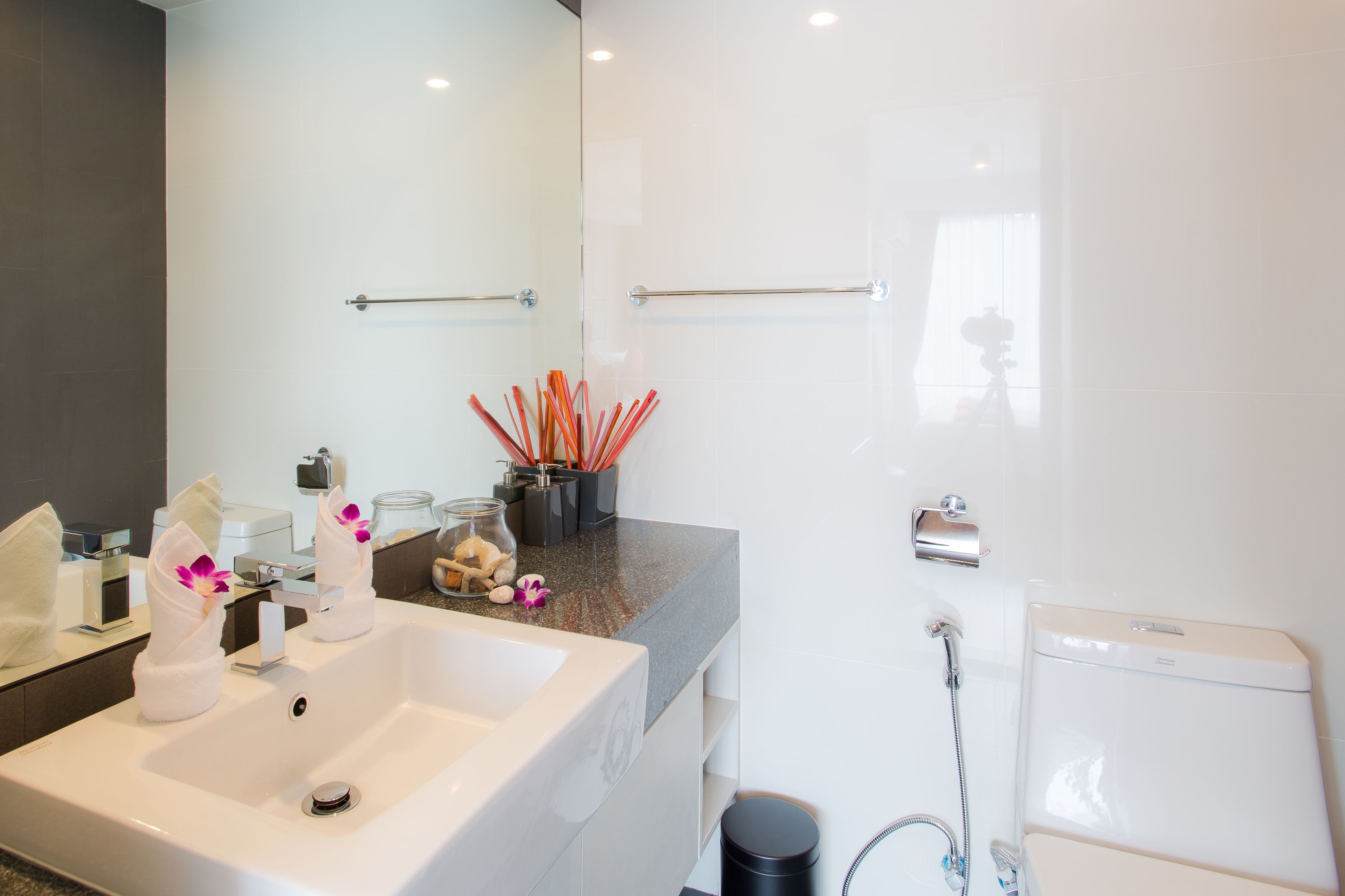 Un baño moderno con un lavamanos grande, espejo y perchero.