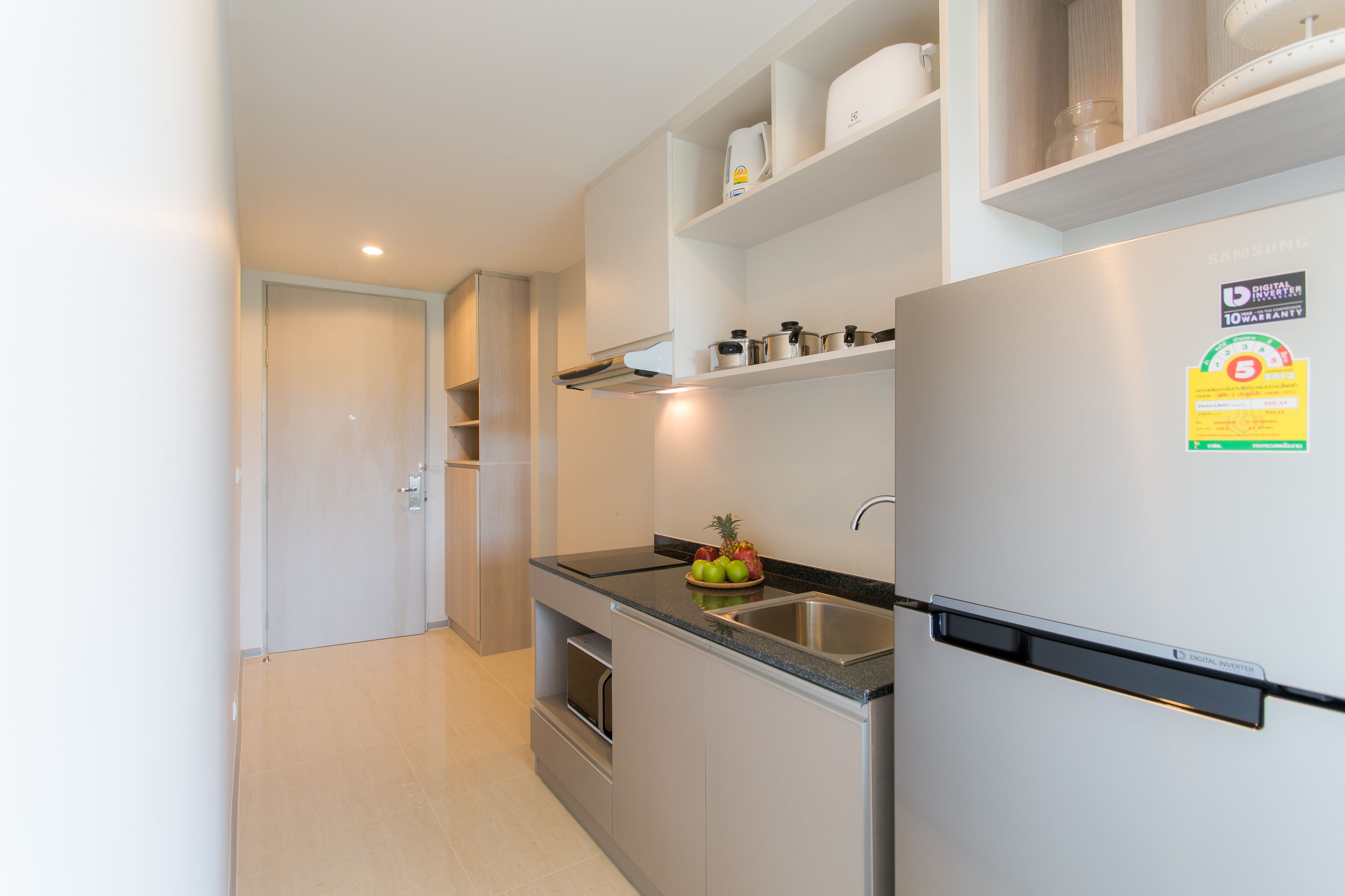 A modern kitchen with a built-in refrigerator, a stainless steel sink, and a microwave. There are shelves above the counter holding kitchenware.