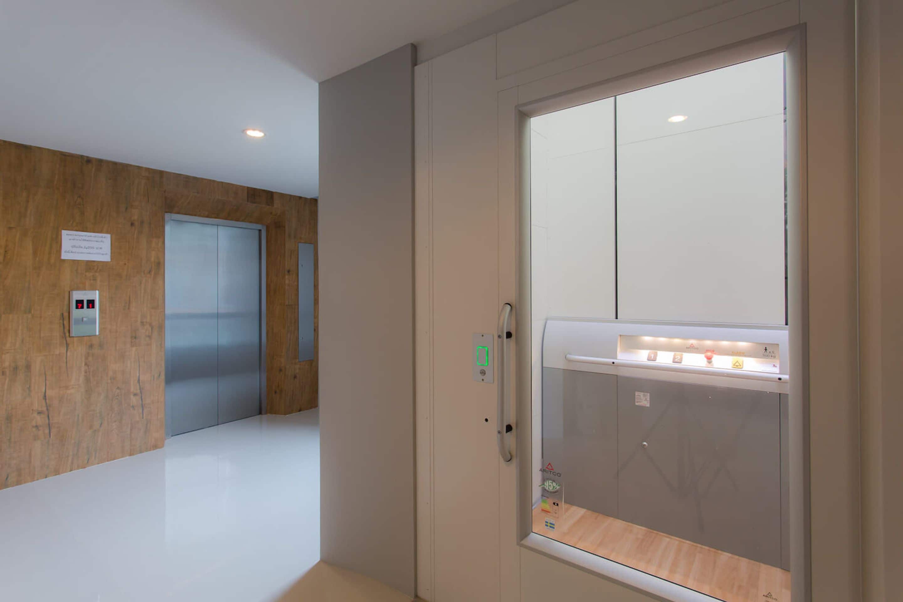 A modern elevator with a control panel and emergency buttons.