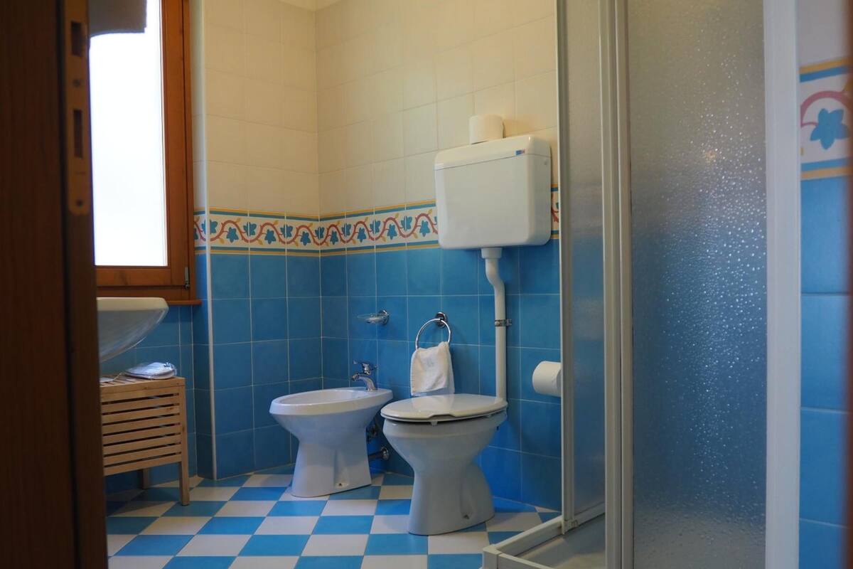 A bathroom with a checkered floor, two toilets, a sink, and a shower area.