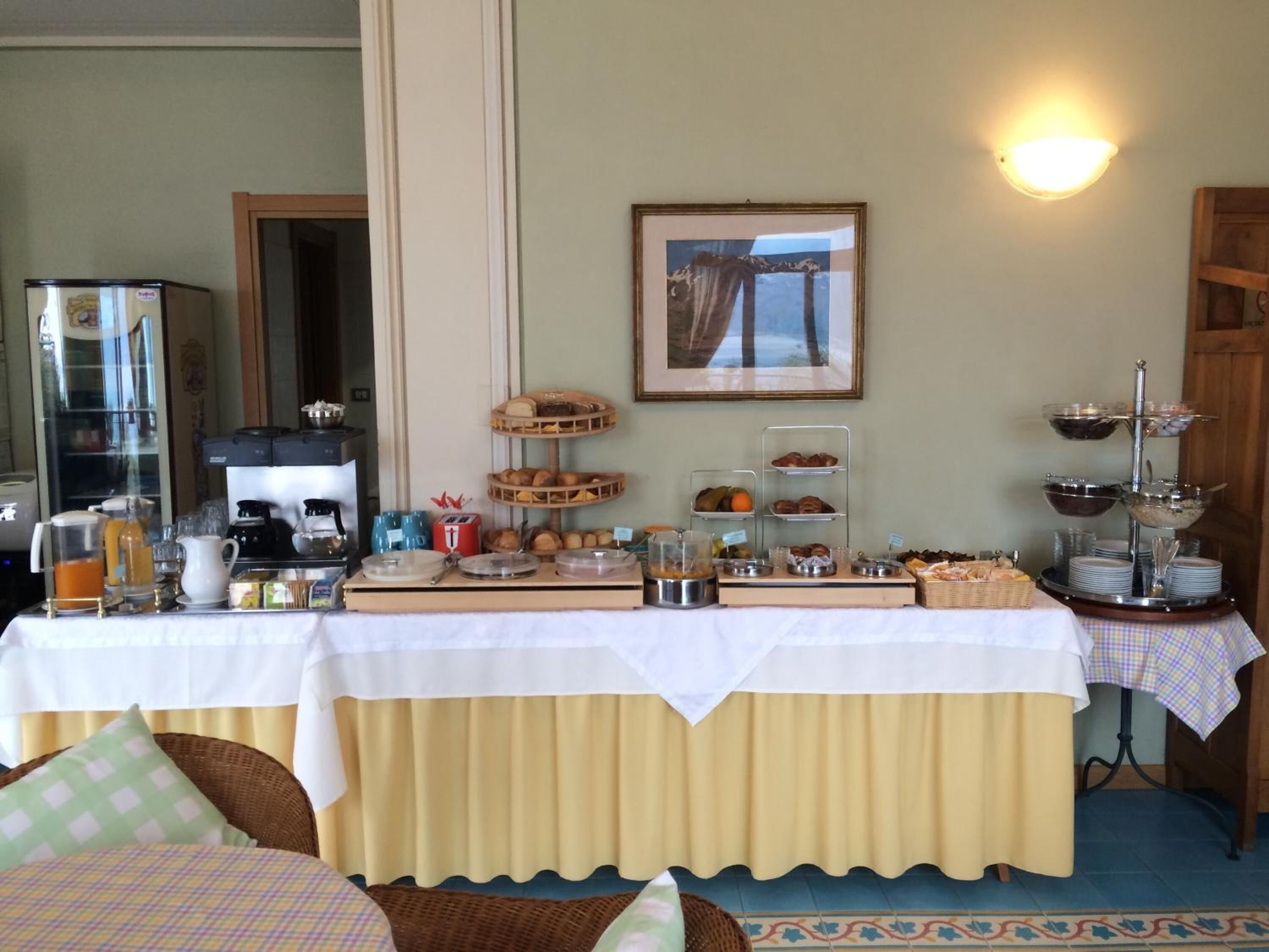 Un buffet de petit-déjeuner avec divers plats, une machine à café et un tableau encadré accroché au mur.