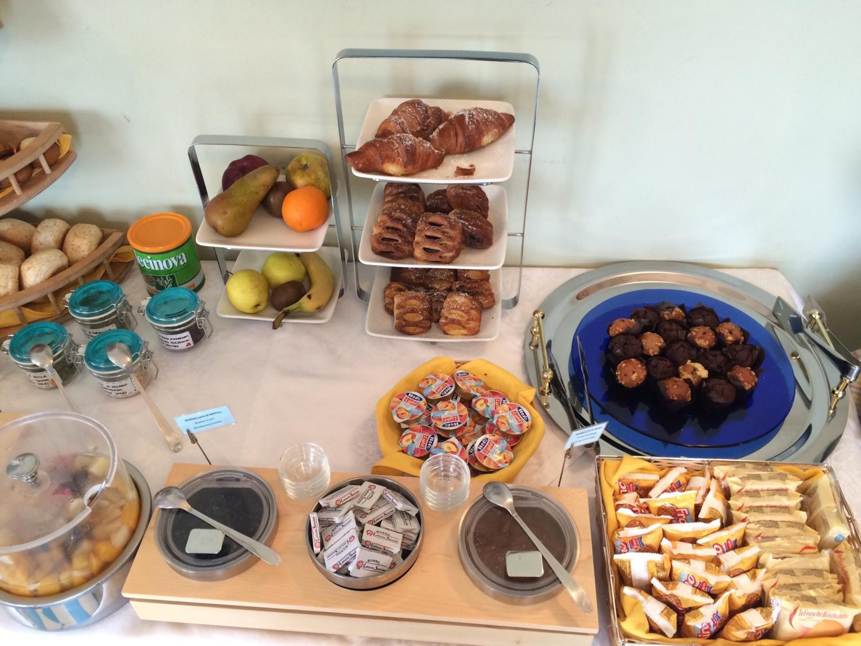 A buffet table with various food items including fruits, pastries, and desserts.