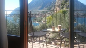 A balcony with a table and chairs, overlooking a mountainous landscape and a body of water. - Hotel Locanda Ruscello Garnì (Limone sul Garda)