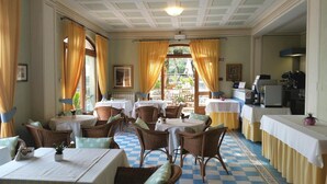 A dining area with wicker furniture, checkered floor, and yellow curtains. - Hotel Locanda Ruscello Garnì (Limone sul Garda)