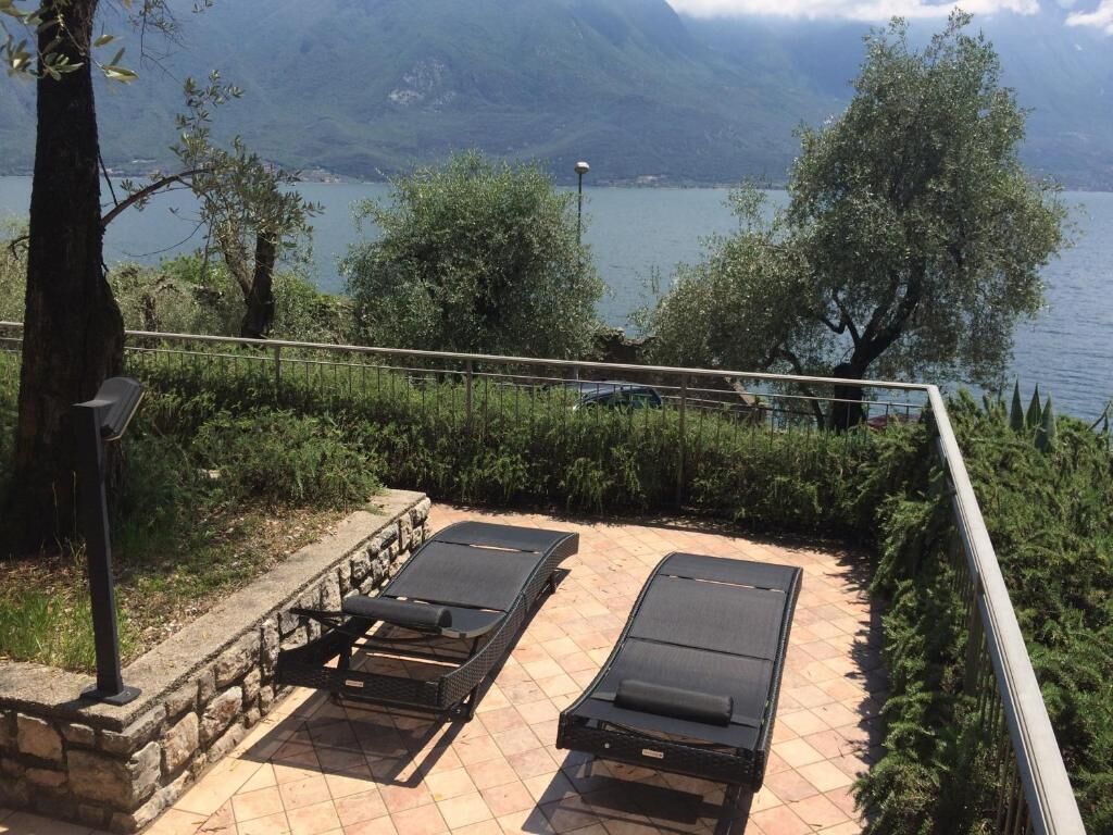 Dos tumbonas en un patio empinado con vista a un lago y montañas.