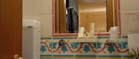 A bathroom with a white sink, a mirror with a pink frame, and a blue tiled wall.
