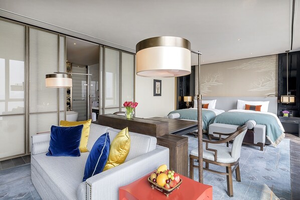 A modern hotel room with a sofa, a dining table, a fruit bowl, and a bed with two pillows. - Hangzhou Jiutai Hotel (Hangzhou)