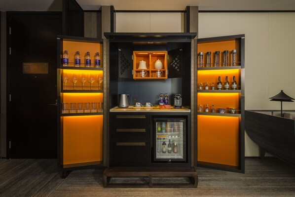 A compact minibar with shelves of bottled water, wine glasses, and a mini-fridge. -  Hangzhou Jiutai Hotel (Hangzhou)