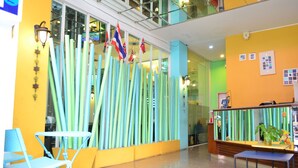 Zona de recepción con separador de vidrio, sillas azules y mostrador de madera.