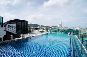 A rooftop infinity pool with clear blue tiles, a glass balustrade, and a modern building structure in the background. - Centro at Sansabai (Patong)