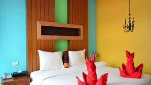 Una habitación de hotel con cabecera de madera, cama con ropa blanca y almohadas decorativas rojas.