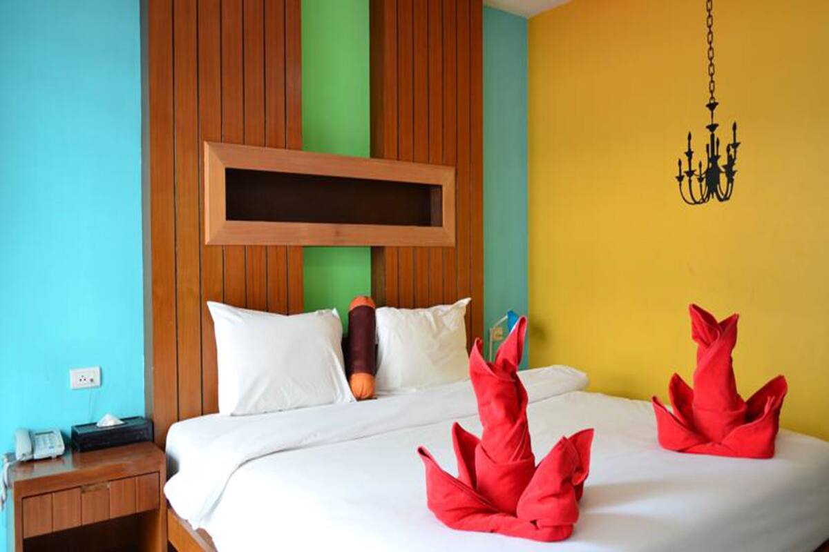 Une chambre d’hôtel avec une tête de lit en bois, un lit avec une literie blanche et des coussins décoratifs rouges.