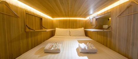 Una habitación de hotel con techo de madera, una cama grande con ropa blanca y un espejo en la pared.