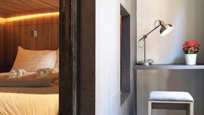 Een hotelkamer met een bed, een bureau, een lamp en een klein bankje.