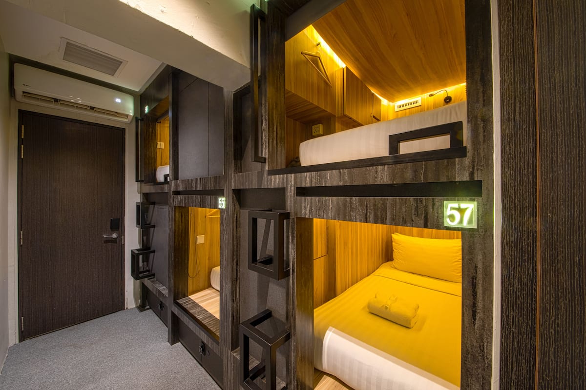 Quarto com beliches, uma porta e uma placa com o número 57 na parede.