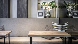 Een modern interieur met een bank, twee tafels en decoratieve vazen met bloemen.