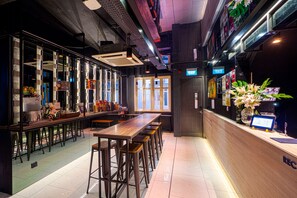 Un bar moderno con taburetes altos, una barra de madera y un ventanal grande.