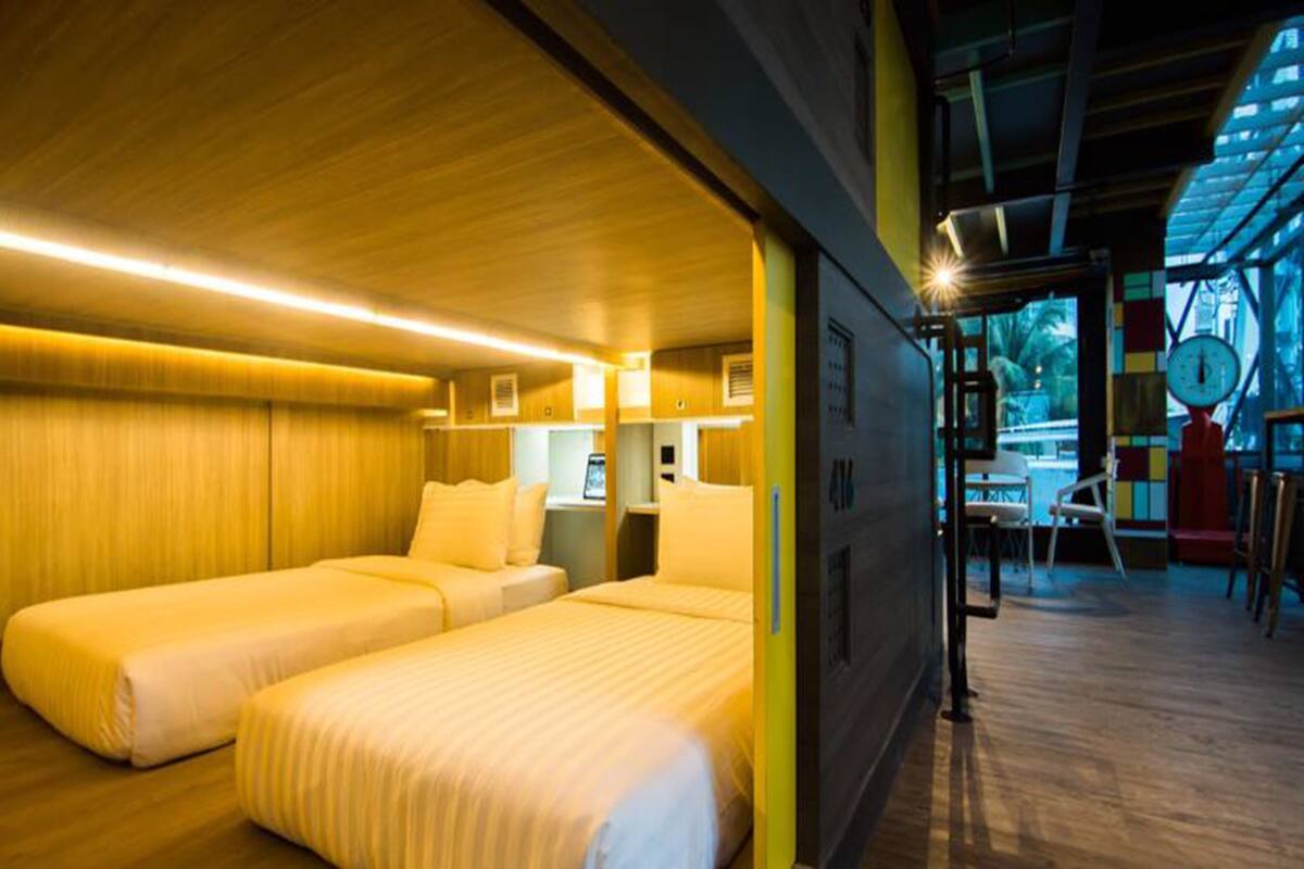 A room with two beds, wooden walls, and a window with a view of palm trees.