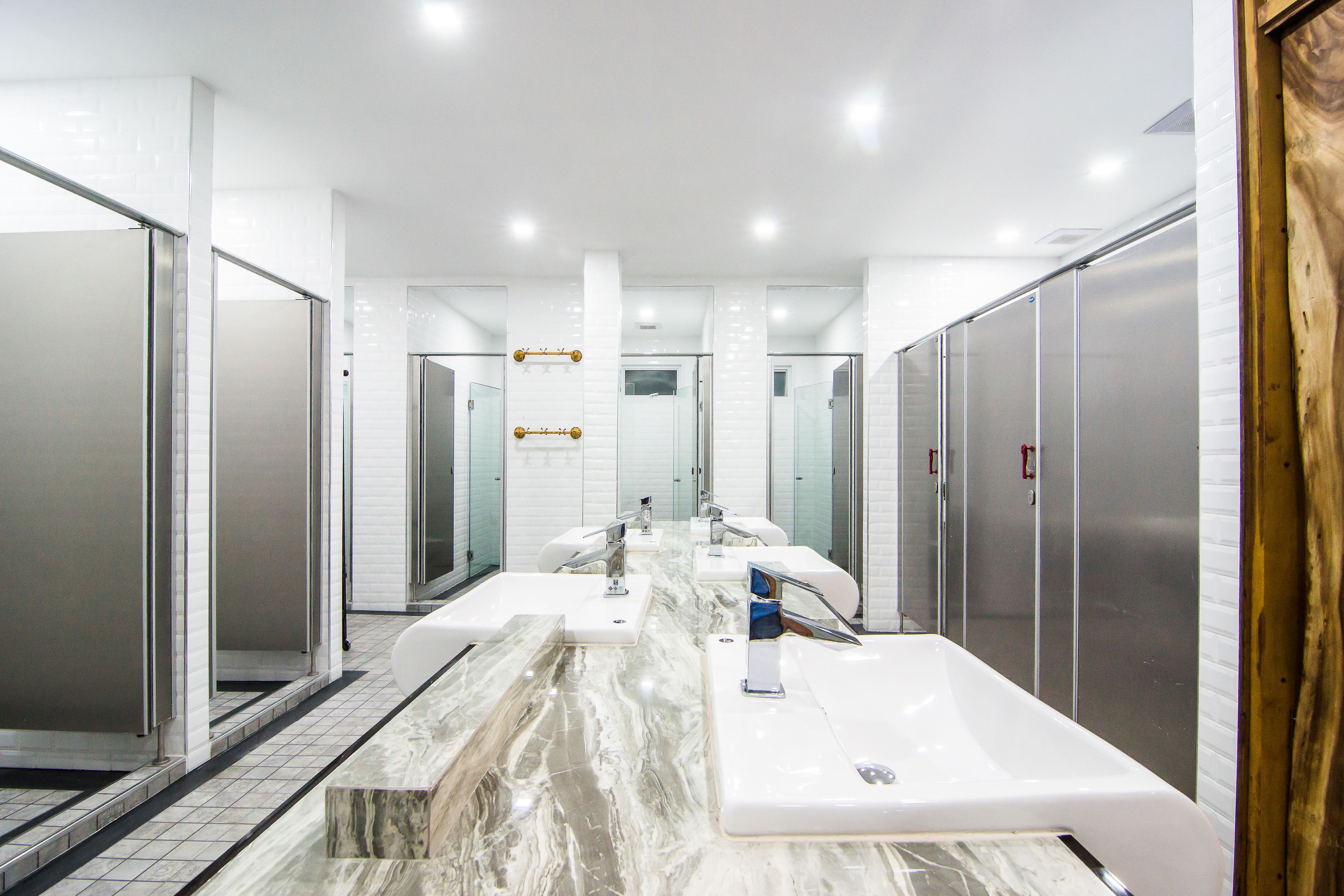 Une salle de bain moderne dotée de plusieurs lavabos, d’un comptoir en marbre et d’une cabine de douche en verre.