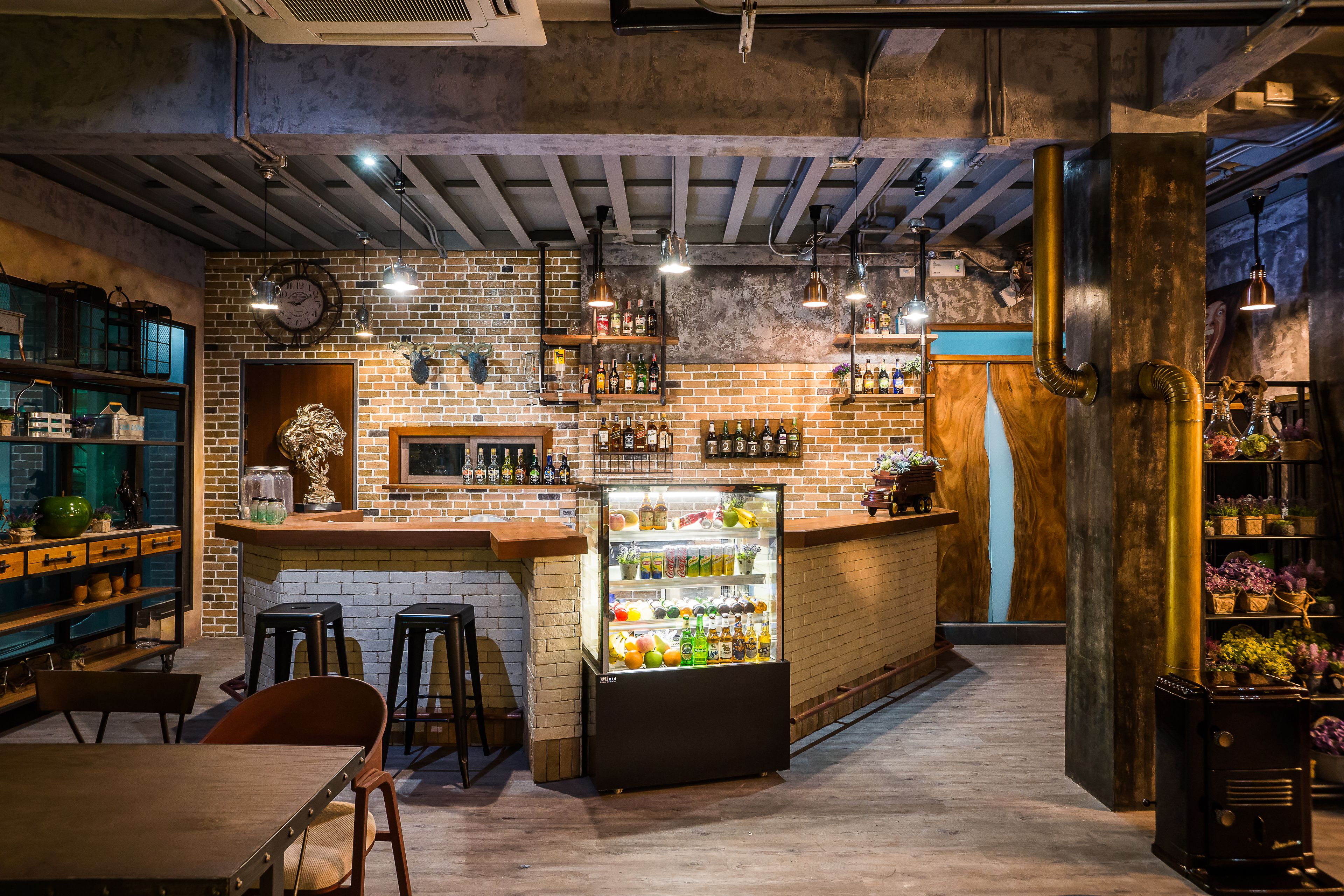A bar area with a brick wall, wooden shelves, and a refrigerated display case.