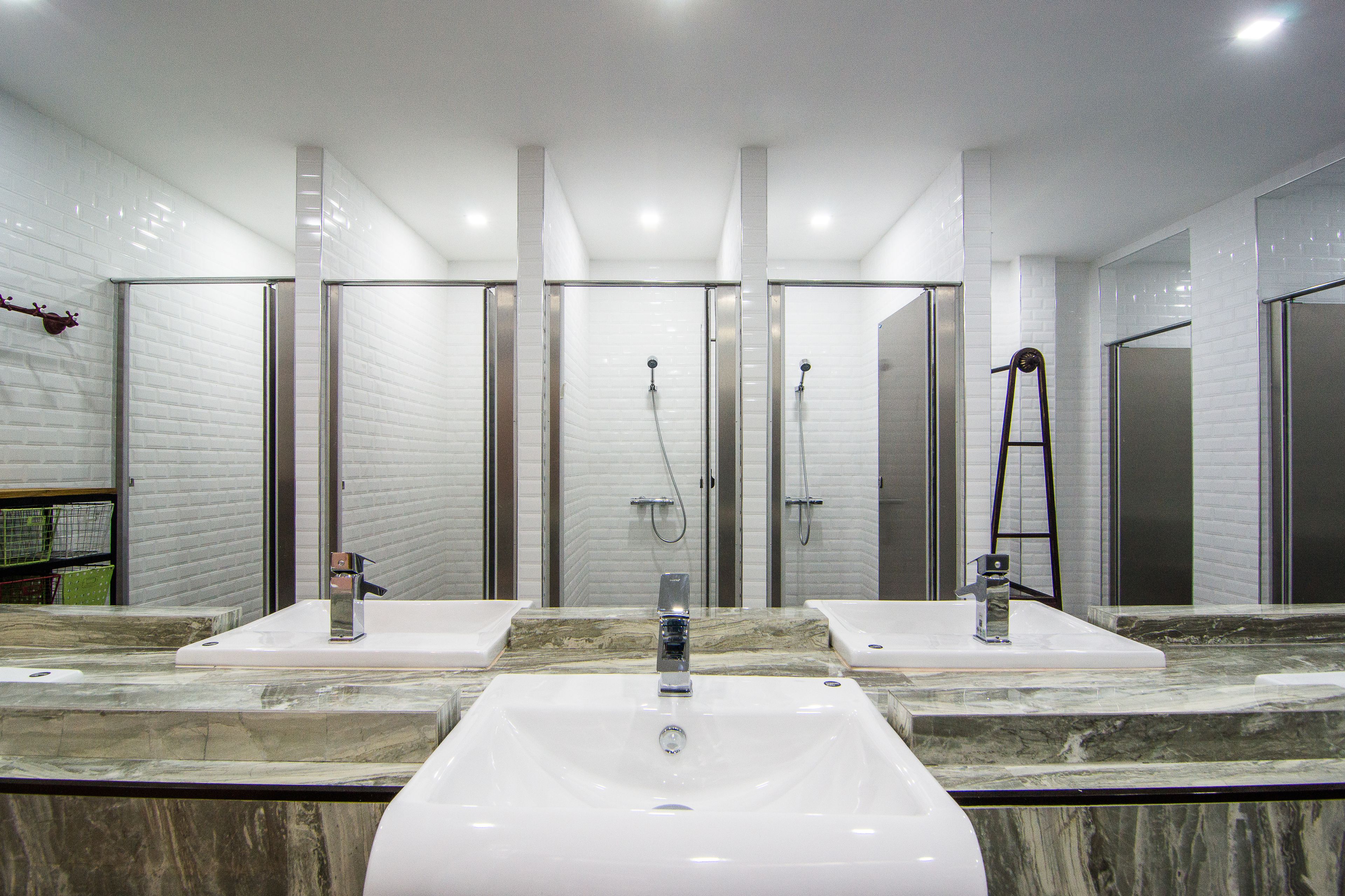 A modern bathroom with a large central sink, two side sinks, and a glass-enclosed shower area.