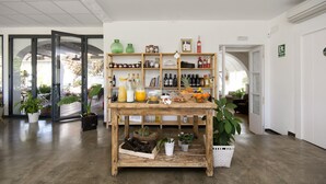 Een kamer met een houten tafel waarop verschillende flessen en fruit staan, omringd door kasten vol flessen en een brandblusser.