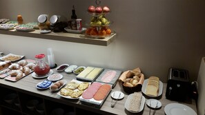 A buffet with various food items including pastries, meats, and fruits.
