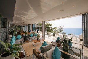 Un interior moderno con una zona de estar, ventanas amplias y vistas al mar.