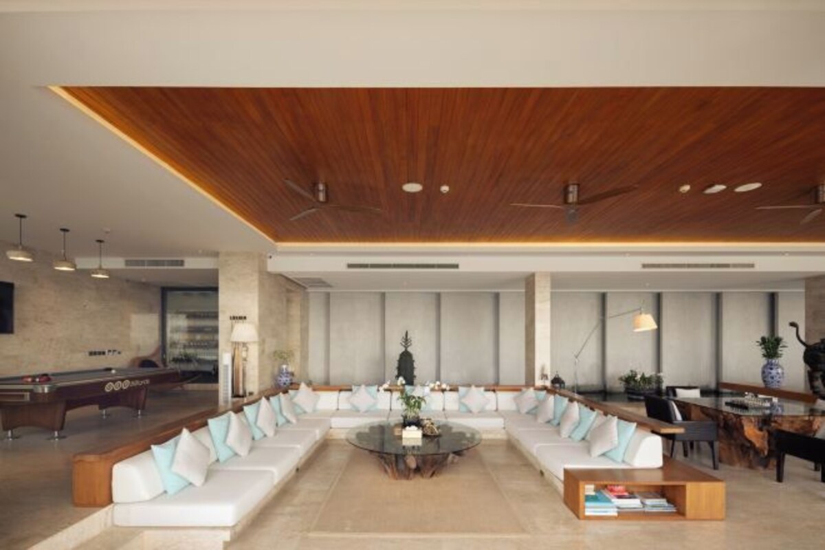 A modern lobby with a pool table, seating area, and a wooden ceiling.