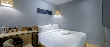 Habitación de hotel con cama, escritorio, silla y una obra de arte colgada en la pared.