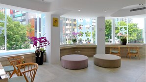 A modern hotel lobby with large windows, wooden chairs, a round seating area, and potted plants. - SSBHotel - Shin Sei Bashi (Taichung)