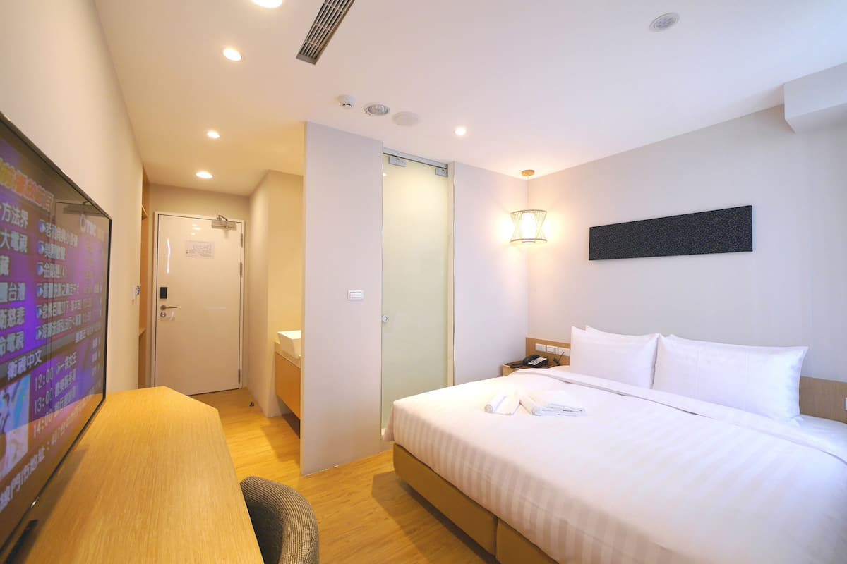 A hotel room with a bed, bedside table, and a television screen displaying a menu.