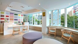 A modern interior with a reception desk, seating area, and large windows offering a view of greenery and buildings. - SSBHotel - Shin Sei Bashi (Taichung)
