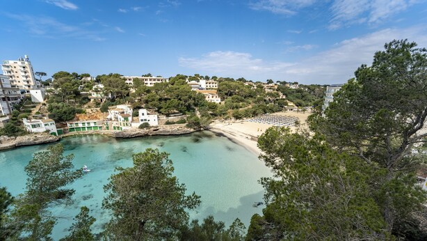Un pueblo costero con playa, edificios y un mar turquesa transparente.