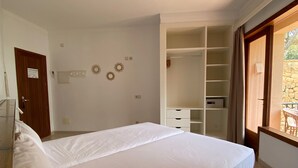 Un dormitorio con una cama grande, un armario, un escritorio y vistas al exterior.