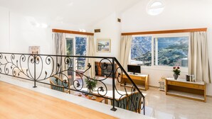 Een ruime woonkamer met balkon, grote ramen met uitzicht op de bergen en een moderne trap.