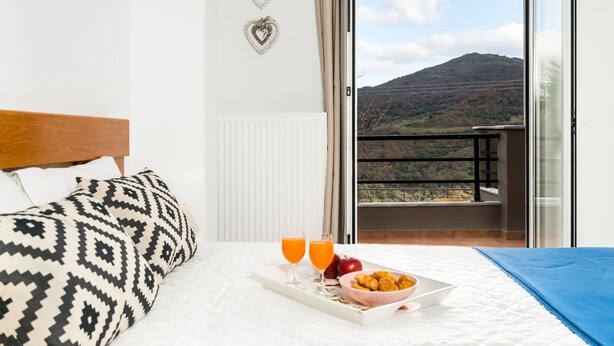 Een hotelkamer met een bed, een ontbijtplateau met sinaasappelsap en uitzicht op een berg.
