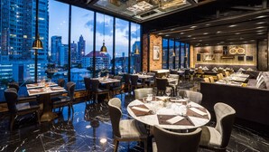 A modern restaurant with large windows offering a city view, polished marble floors, and contemporary furniture. - SKYVIEW Hotel Bangkok (Bangkok)