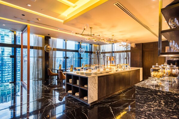A modern bar area with a marble countertop, glass shelves, and a city view. - SKYVIEW Hotel Bangkok (Bangkok)