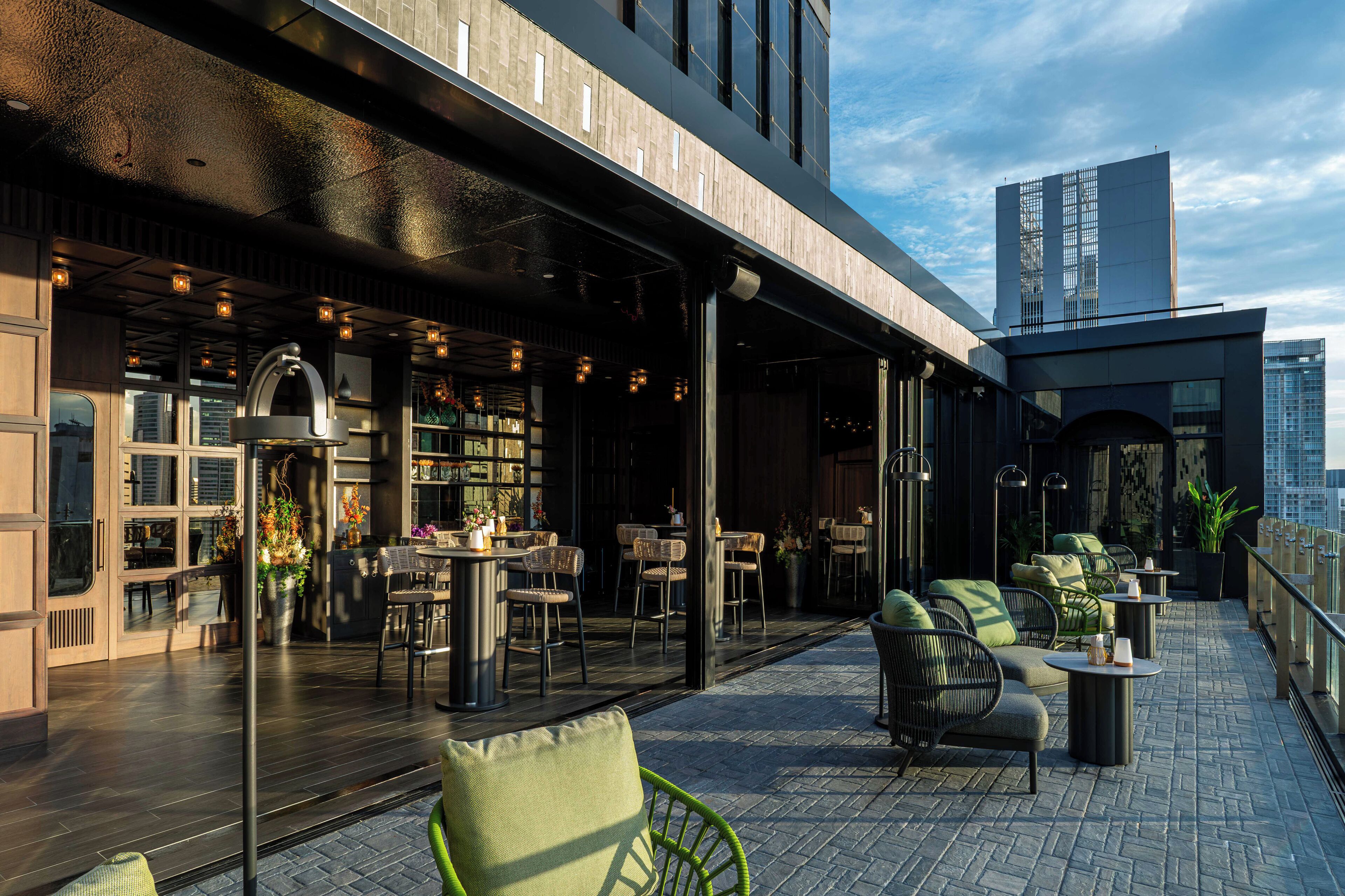 An outdoor seating area with tables and chairs, a bar, and a view of the city skyline.