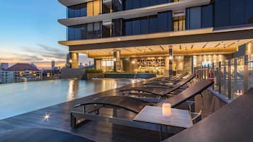 Una piscina al aire libre, sombrillas, sillones reclinables de piscina