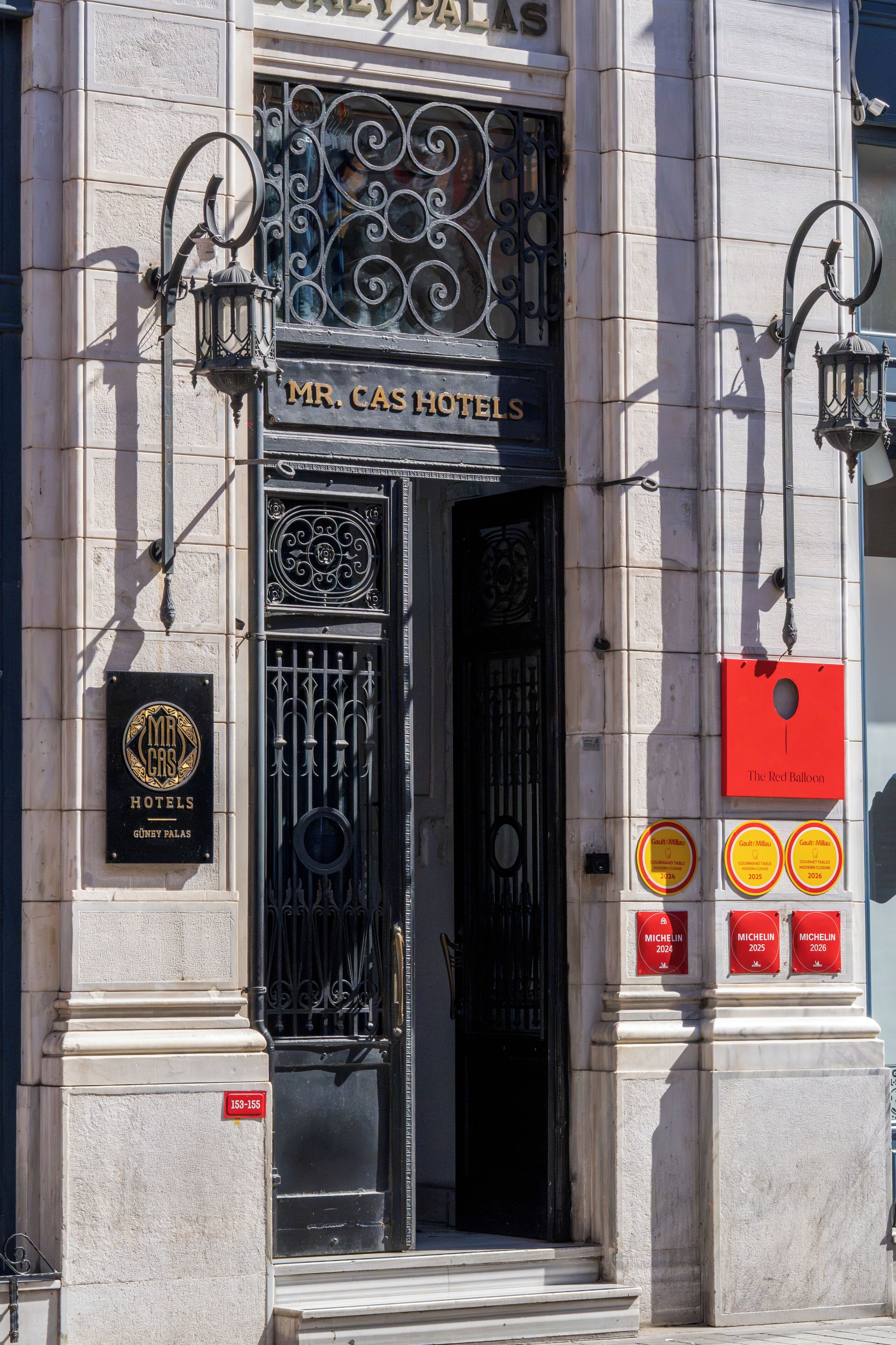 The entrance to Mr. Cas Hotels with ornate ironwork, a black door, and a plaque indicating Michelin awards for 2024, 2025, and 2026.