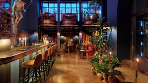 Zona de bar con taburetes, una estatua y una escalera que lleva a un entrepiso.