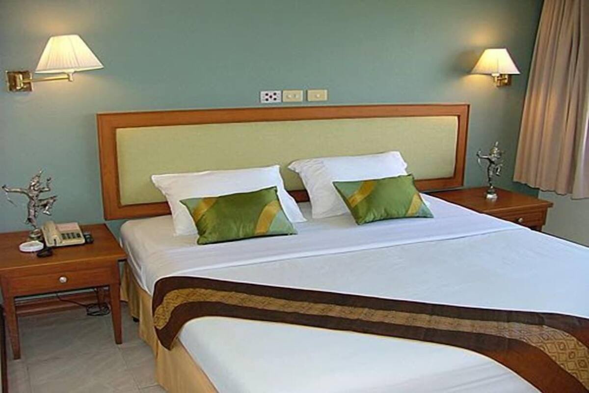 Ein Hotelzimmer mit einem großen Bett, zwei Nachttischlampen, einem Telefon auf dem Nachttisch und einem dekorativen Gegenstand auf dem Nachttisch.