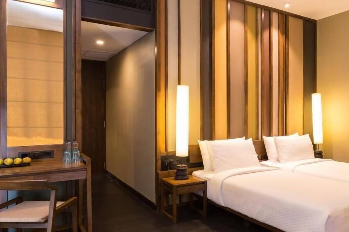 A hotel room with a bed, bedside tables, a desk, and a chair.