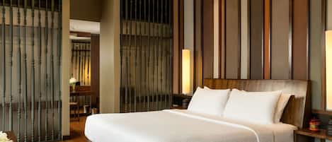 A modern hotel room with a large bed, wooden headboard, and a ceiling fan.
